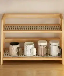 A two-tier wooden shelf holding four ceramic mugs with different patterns and colors on the bottom shelf. | 28Alchemy