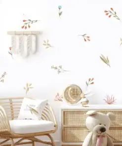 A cozy nursery with a rattan chair, teddy bear, dresser, and floral wall decals on a white wall. | 28Alchemy