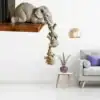 Elephant sculptures hang off a shelf, trunk-to-tail, above a modern living room with a purple-accented table and sofa. | 28Alchemy