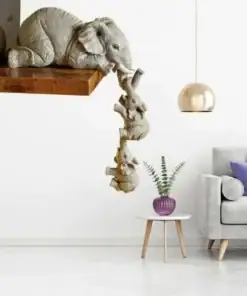 Elephant sculptures hang off a shelf, trunk-to-tail, above a modern living room with a purple-accented table and sofa. | 28Alchemy