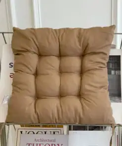 A tan, tufted cushion sits on a shelf above neatly arranged magazines and books. | 28Alchemy