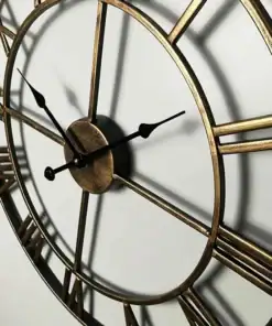 A close-up of a round, vintage wall clock with Roman numerals and black hands, casting shadows on a white wall. | 28Alchemy