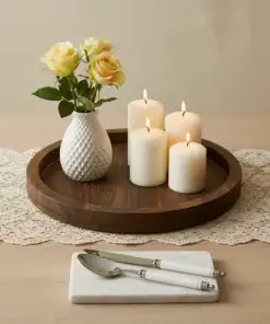 A wooden tray holds a white vase with yellow roses and four lit candles on a lace runner, with cutlery on a marble rest. | 28Alchemy