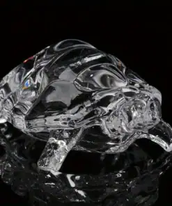 Clear glass turtle figurine on a black surface, showing detailed shell and limbs with light reflections. | 28Alchemy