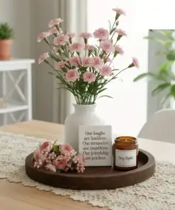 A vase of pink flowers, a candle, and a friendship quote sit on a wooden tray atop a lace-covered table. | 28Alchemy