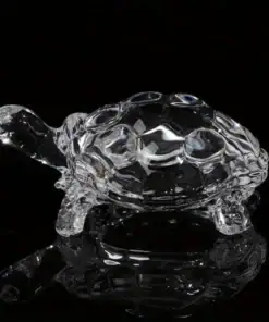 A clear glass turtle figurine is displayed against a black background with a reflective surface. | 28Alchemy