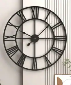 Large black metal wall clock with Roman numerals hangs on a modern white paneled wall above minimal home decor. | 28Alchemy