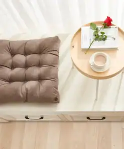 A brown cushion next to a small round table holding a red rose, a book, and a cup of coffee. | 28Alchemy