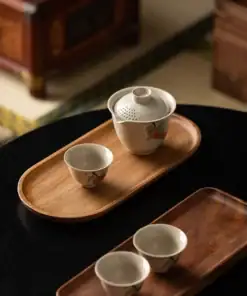 Chinese tea set with a teapot and three cups on wooden trays, placed on a dark table in a cozy room. | 28Alchemy