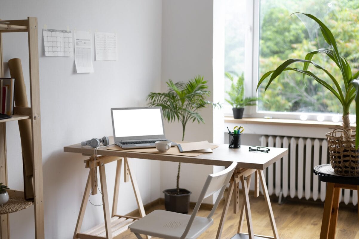 Minimalist home office with a wooden desk, laptop, plants, and a window with greenery outside. | 28Alchemy