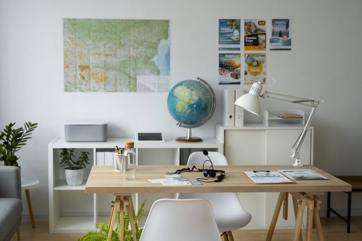 A modern office with a desk, chairs, globe, maps, plants, travel brochures, and wall posters. | 28Alchemy