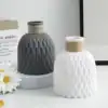 Two textured vases, one gray and one white, with rope details on top; daisies in foreground and paper decor in background. | 28Alchemy