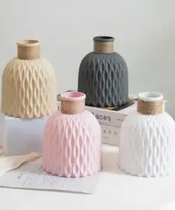 Four textured vases in beige, gray, pink, and white on a table with books and papers in the background. | 28Alchemy