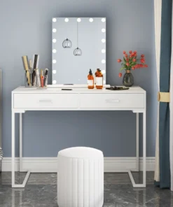 White vanity table with mirror framed by lights, makeup items, bottles, and a vase of red tulips, next to a stool. | 28Alchemy