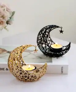 Gold and black crescent moon candle holders with lit candles on a table beside a book and a vase of flowers. | 28Alchemy