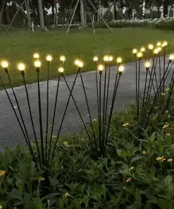 Rows of glowing garden lights on tall stems are arranged among green plants along a sidewalk at dusk. | 28Alchemy