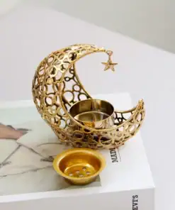 Golden crescent moon candle holder with a hanging star and small dish, placed on a book on a white surface. | 28Alchemy