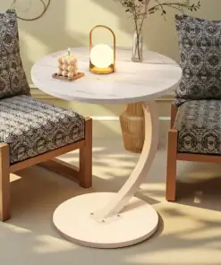 Round white table with a candle, small lamp, and vase, placed between two patterned chairs in a cozy room. | 28Alchemy