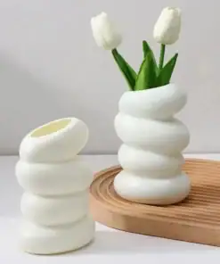 Two white, spiral-shaped vases; one holds two white tulips, both placed on a light wooden tray. | 28Alchemy