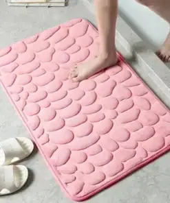 A person steps out of a shower onto a pink textured bath mat with slippers nearby on a tiled floor. | 28Alchemy
