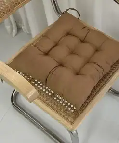 Brown tufted cushion placed on a woven cane chair with metal legs and a light wood frame. | 28Alchemy